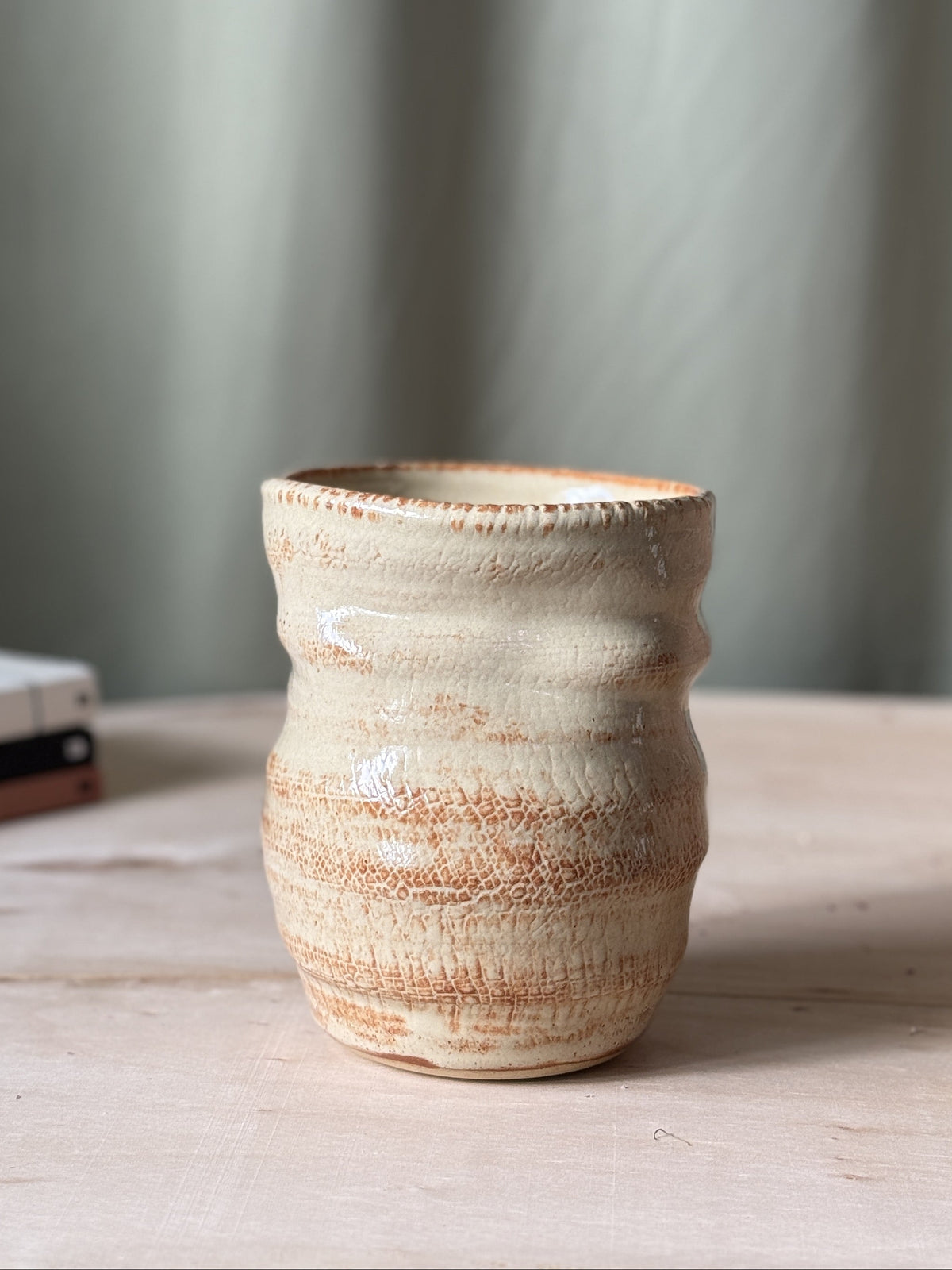 Ceramic textured vase on a wooden surface with a neutral background