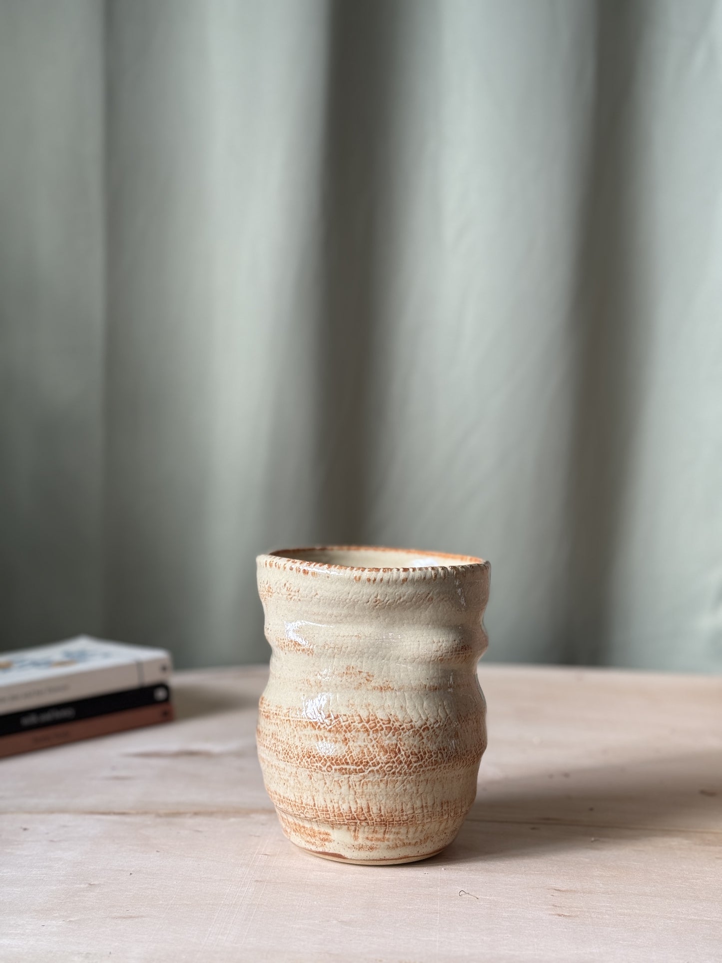 Ceramic textured vase on a wooden surface with a neutral background