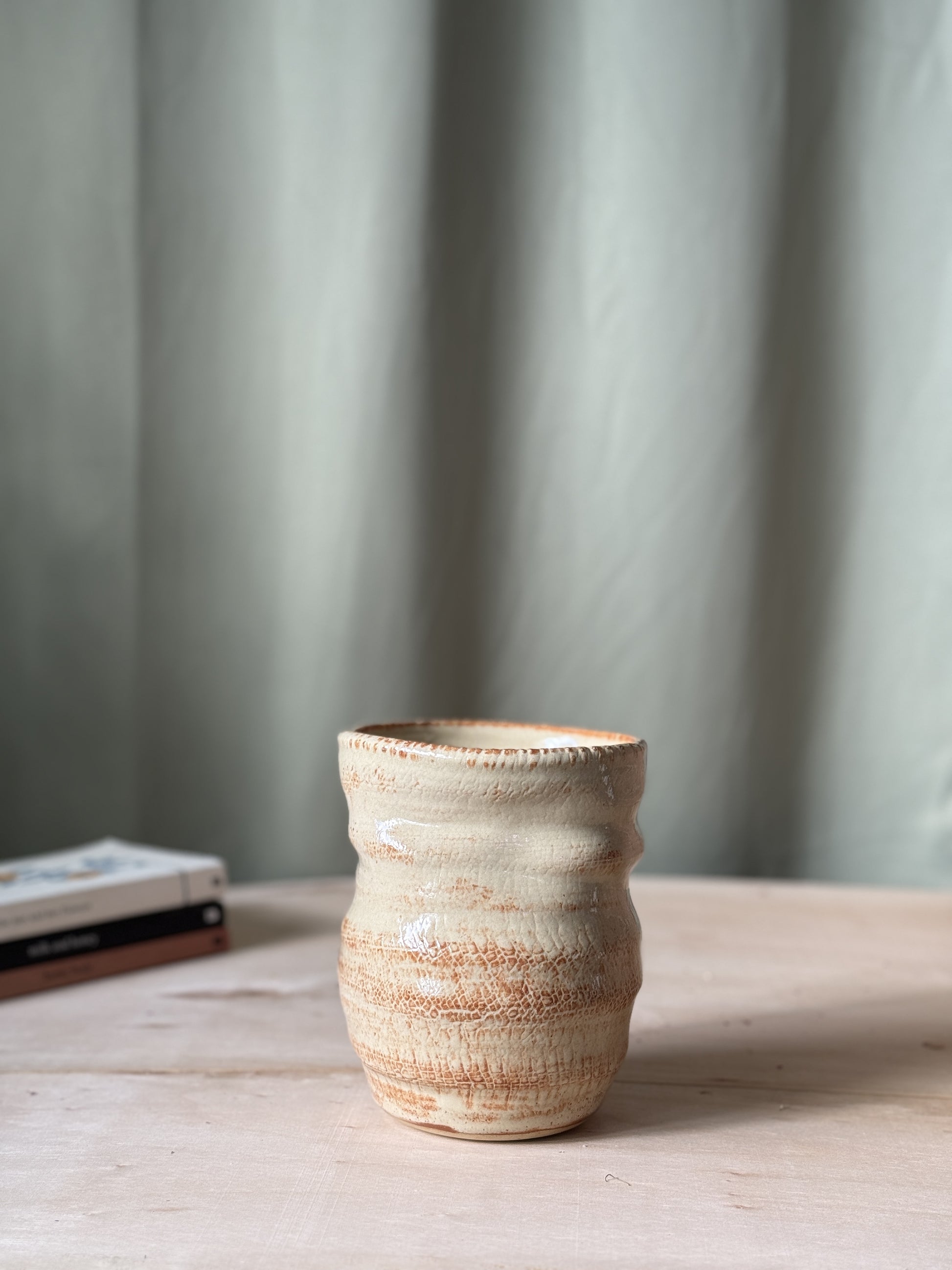 Ceramic textured vase on a wooden surface with a neutral background