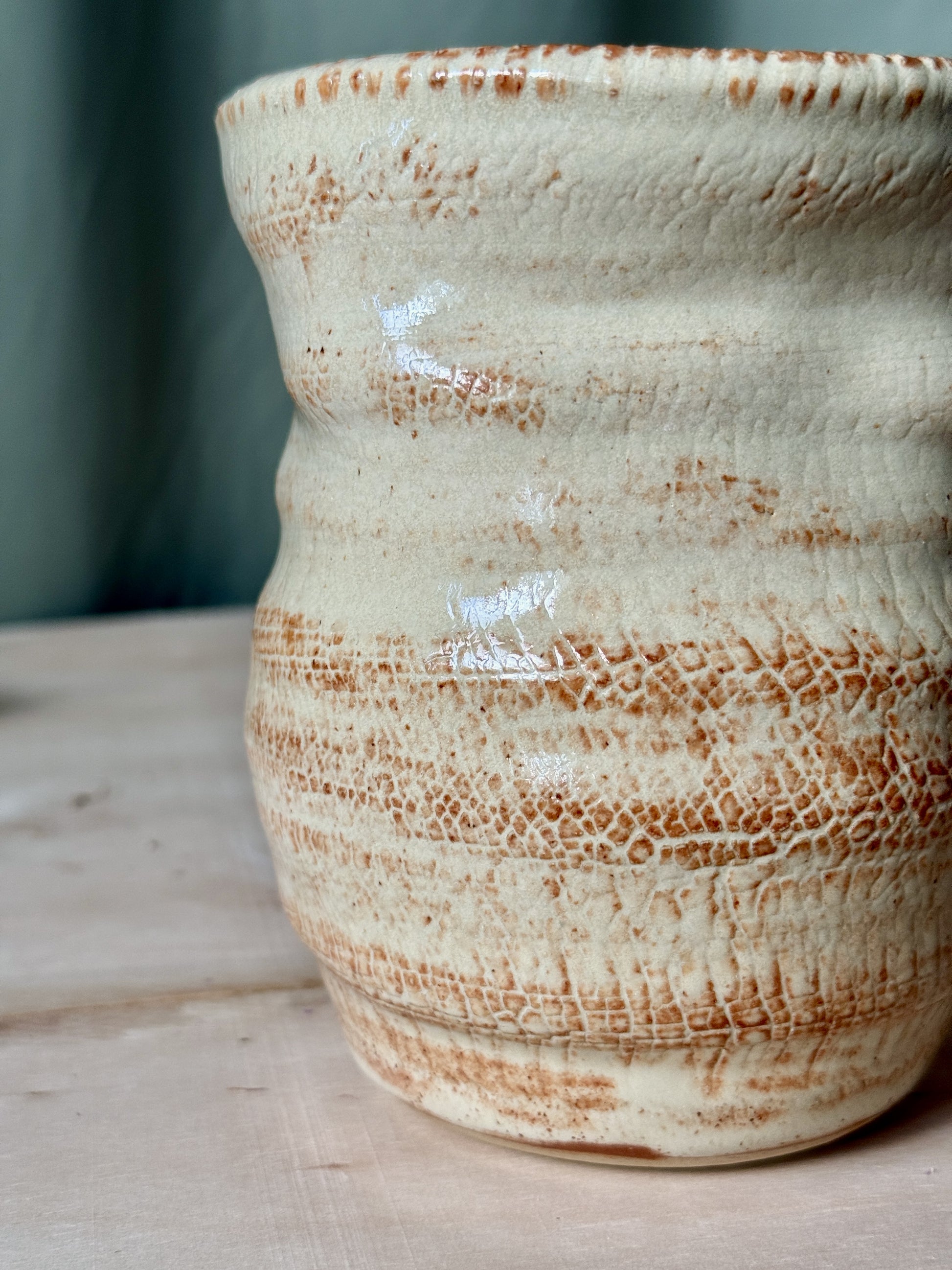 Ceramic texture vase with brown and white glaze on a wooden surface
