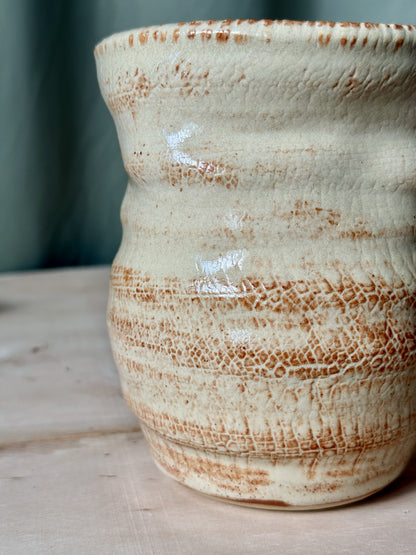 Ceramic texture vase with brown and white glaze on a wooden surface